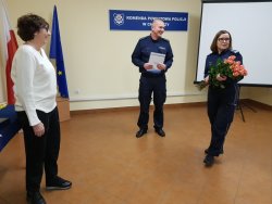 Fotografia przedstawiająca szefową wągrowieckiej Policji podczas przemówienia i wręczenia kwiatów  Alinie Strugała. W tle naczelnik pionu prewencji i rd.