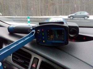 Zdjęcie w kolorze obrazujące urządzenie Trucam na kokpicie radiowozu. W tle na drodze widać samochód osobowy.