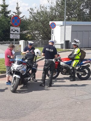 Fotografia w kolorze - policjanci ruchu drogowego zatrzymali do kontroli drogowej kierowców motocykli.