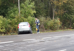 zdjęcie w kolorze - technik kryminalistyczny zabezpiecza dowody w sprawie wypadku drogowego