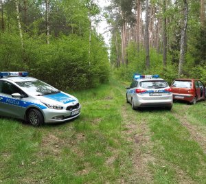 Zdjęcie kolorowe. pojazdy policyjne na drodze leśnej z włączonymi sygnałami błyskowymi