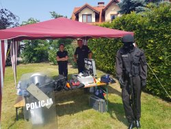 zdjęcie w kolorze - policjant z policjantką stoją na stoisku profilaktycznym Policji.