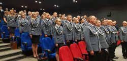 Zdjęcie kolorowe, policjanci w mundurach galowych stojący w sali kinowej ChDK