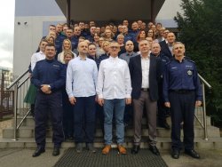zdjęcie w kolorze - wspólna fotografia przed jednostką z policjantami odchodzącymi na emeryturę