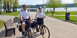 Zdjęcie kolorowe. Policjantka i Policjant pełniący służbę na rowerze na terenie Promenady Jeziora Miejskiego w Chodzieży